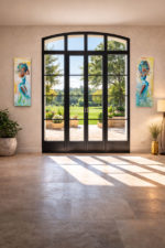 Grand salon lumineux avec baie vitrée donnant sur un jardin, décoré de deux tableaux contemporains de femmes en mouvement réalisés au couteau avec détails en feuille d’or.